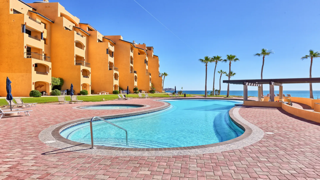 A long, winding turquoise swimming pool surrounded by Mediterranean-style resort buildings.