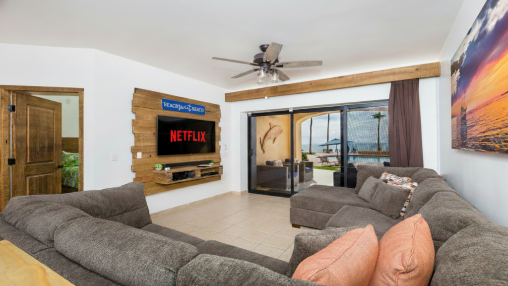 Wide shot of the living room featuring a wall-mounted TV with Netflix and coastal wall art.