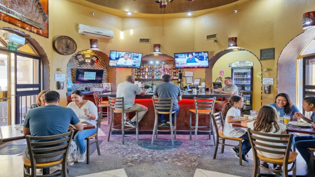 Guests enjoying food and drinks at the modern, circular bar inside the resort cantina.