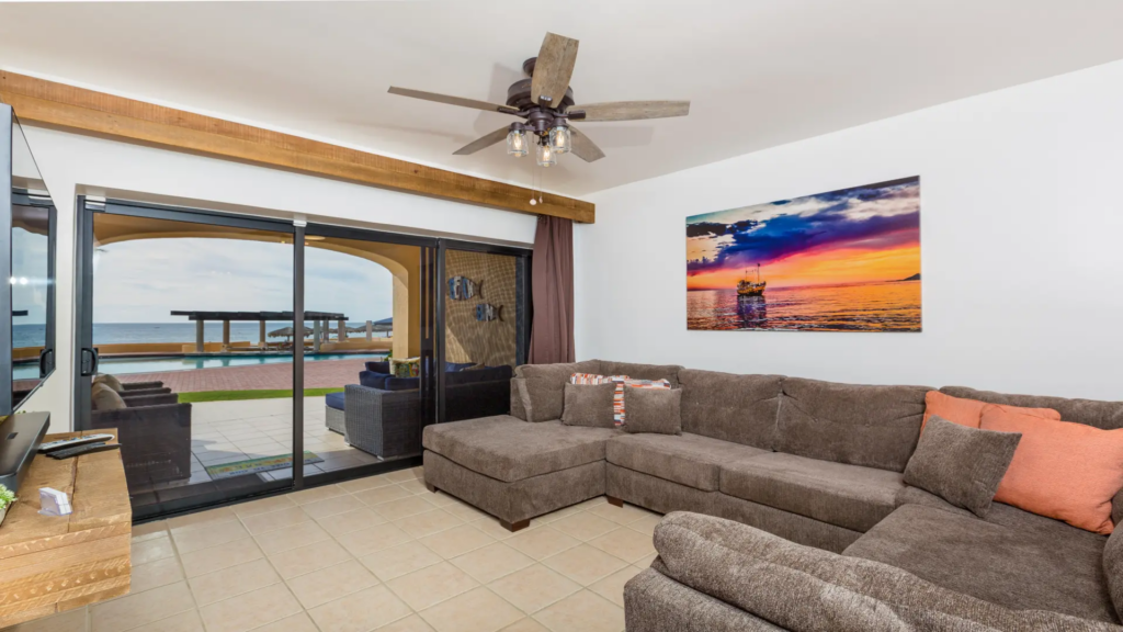 Large sectional sofa in the living room accented by a vibrant sunset painting of a boat.