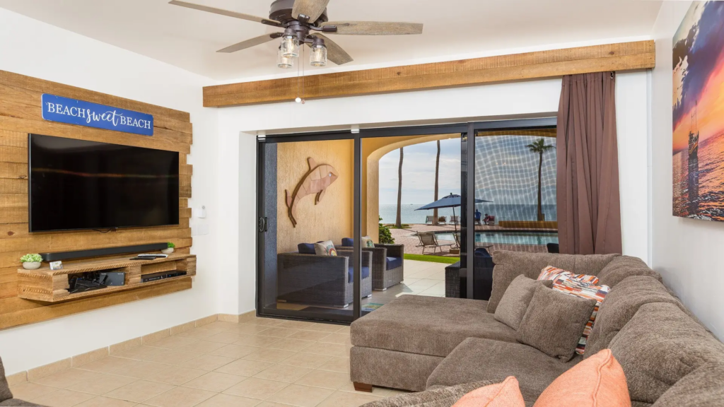 Spacious living room with a brown sectional couch and sliding glass doors opening to a pool.