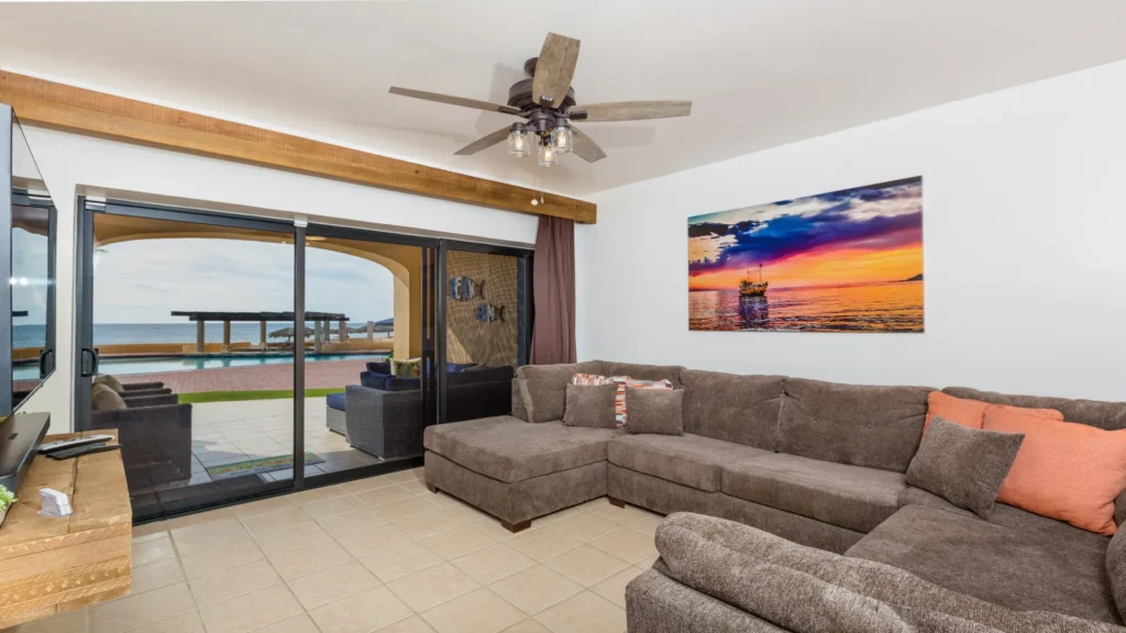 Living room with patio doors overlooking the pool and ocean at beachfront condo