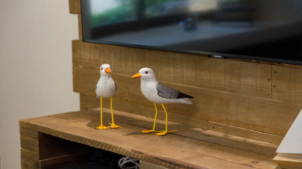 Decorative wooden seagull figurines resting on a rustic wood TV stand.