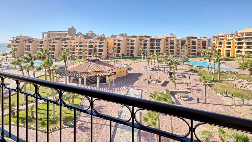 An elevated view from a balcony overlooking the resort's manicured grounds, pools, and walking paths.