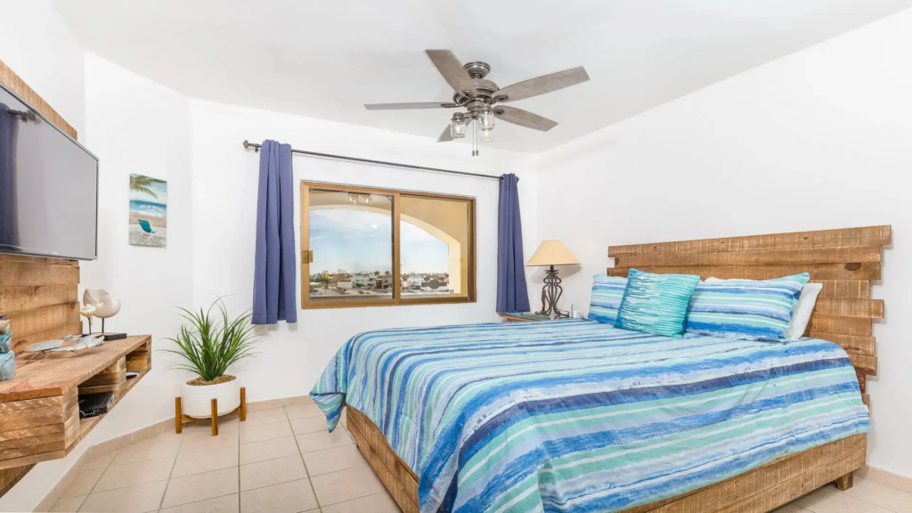 Guest bedroom featuring a rustic wood headboard, blue striped bedding, and a window with a view.