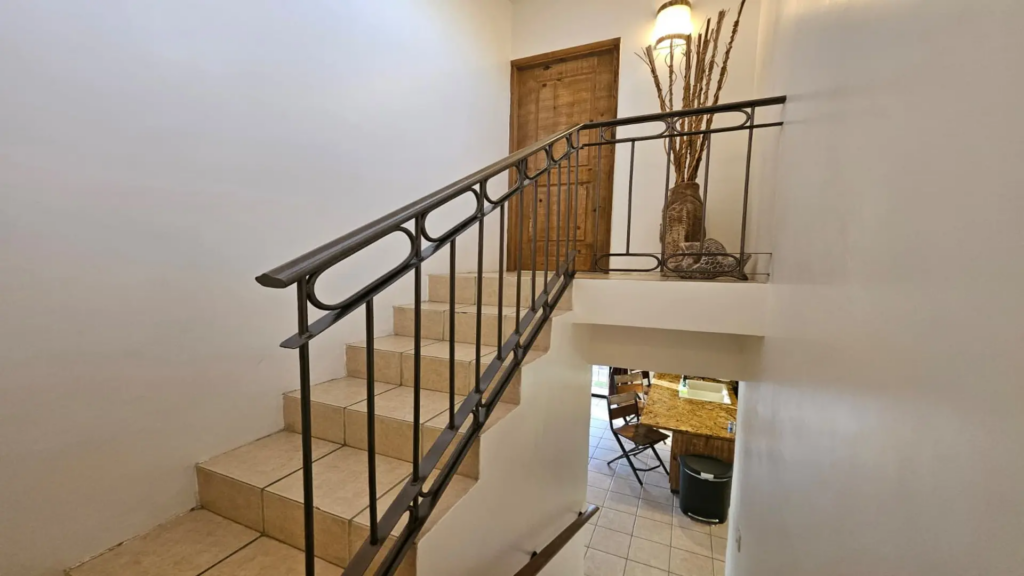 Tiled staircase with an elegant wrought iron railing leading to the upper level of the condo.