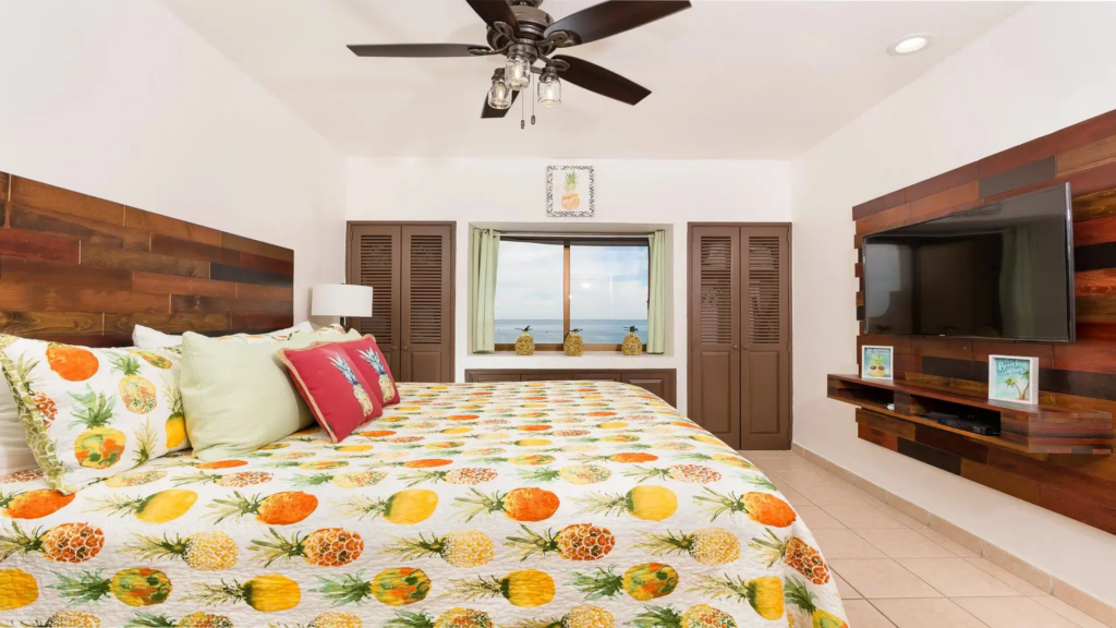 Tropical-themed bedroom with a king bed, pineapple print bedding, and a window seat.