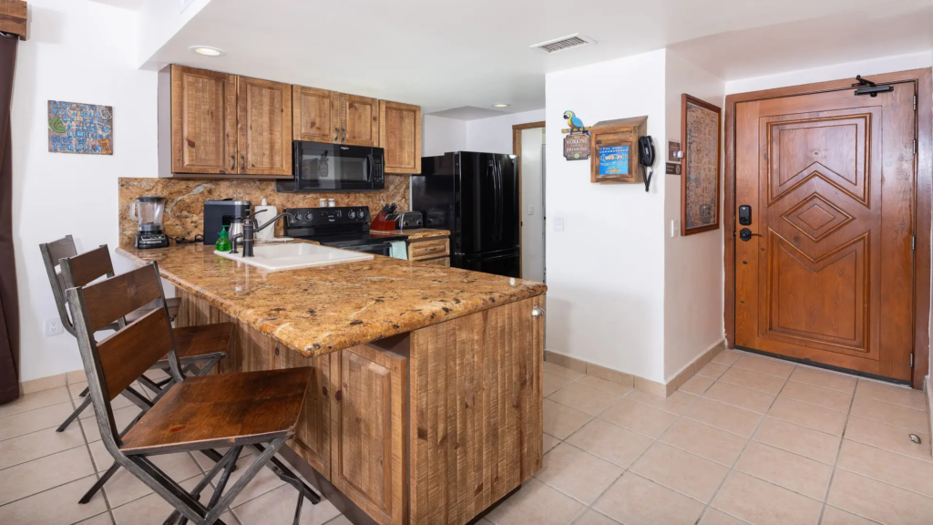 Detailed view of the kitchen featuring warm wood cabinetry, granite counters, and bar seating.