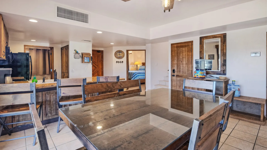 Close-up of a heavy rustic wood dining table with views into the kitchen and hallway.