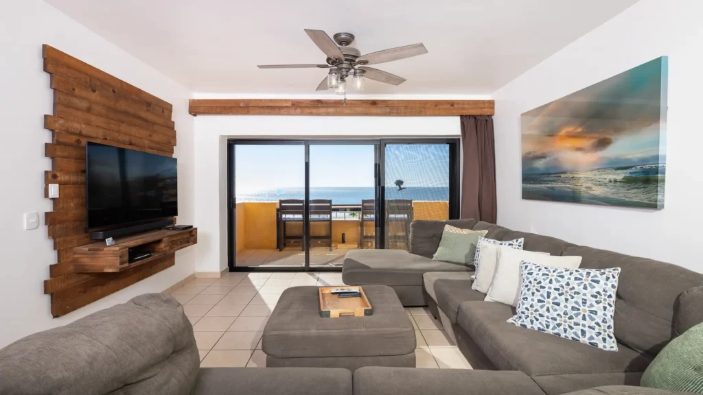 Living room in the E501 2BD two-story penthouse at Princesa Sandy Beach with sliding glass doors and ocean views.