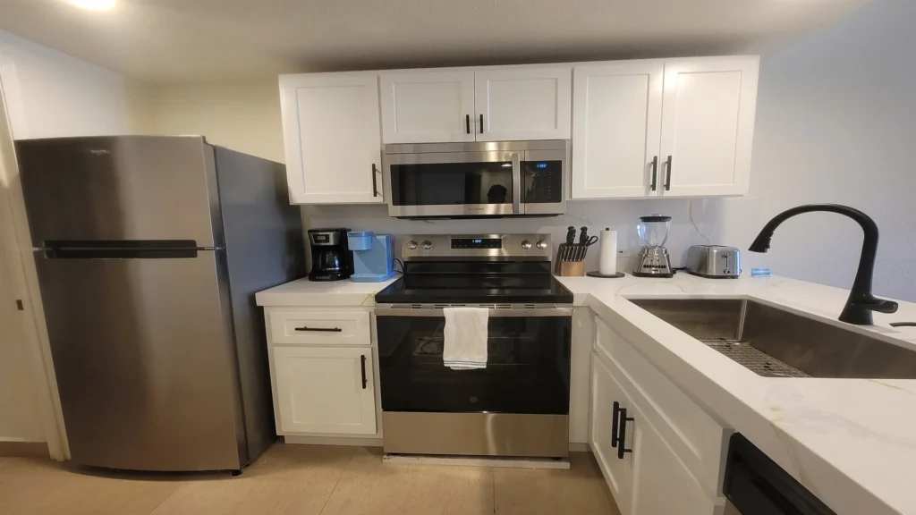 Fully equipped kitchen with oversized single bowl sink, flat top cooktop range, microwave, dishwasher, and fridge